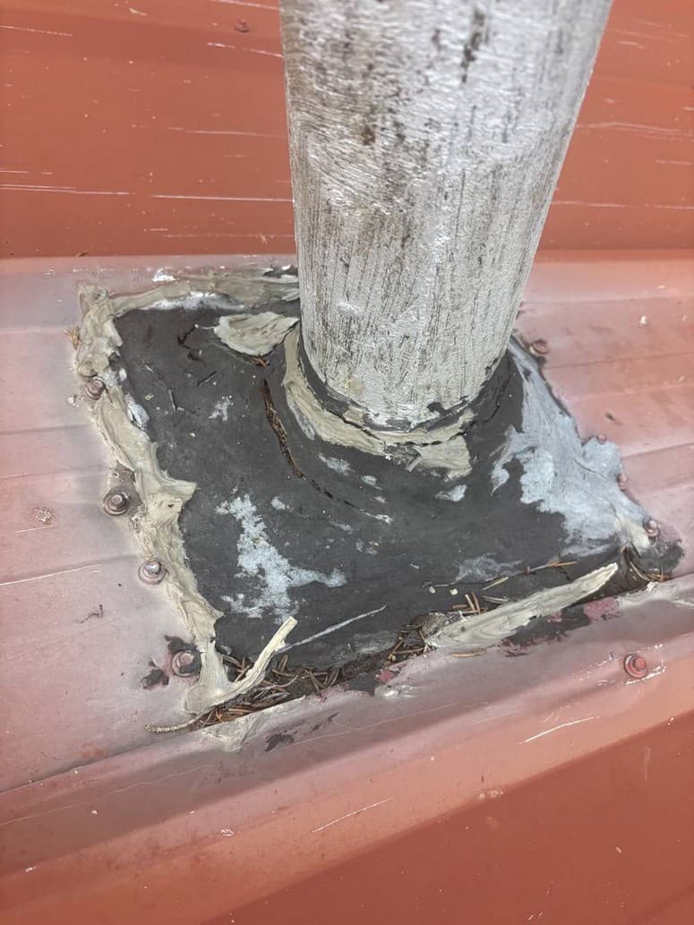 Photo 3 — One of three vents. Asphalt sheet and mastic. Peeling. Needles under the edge.